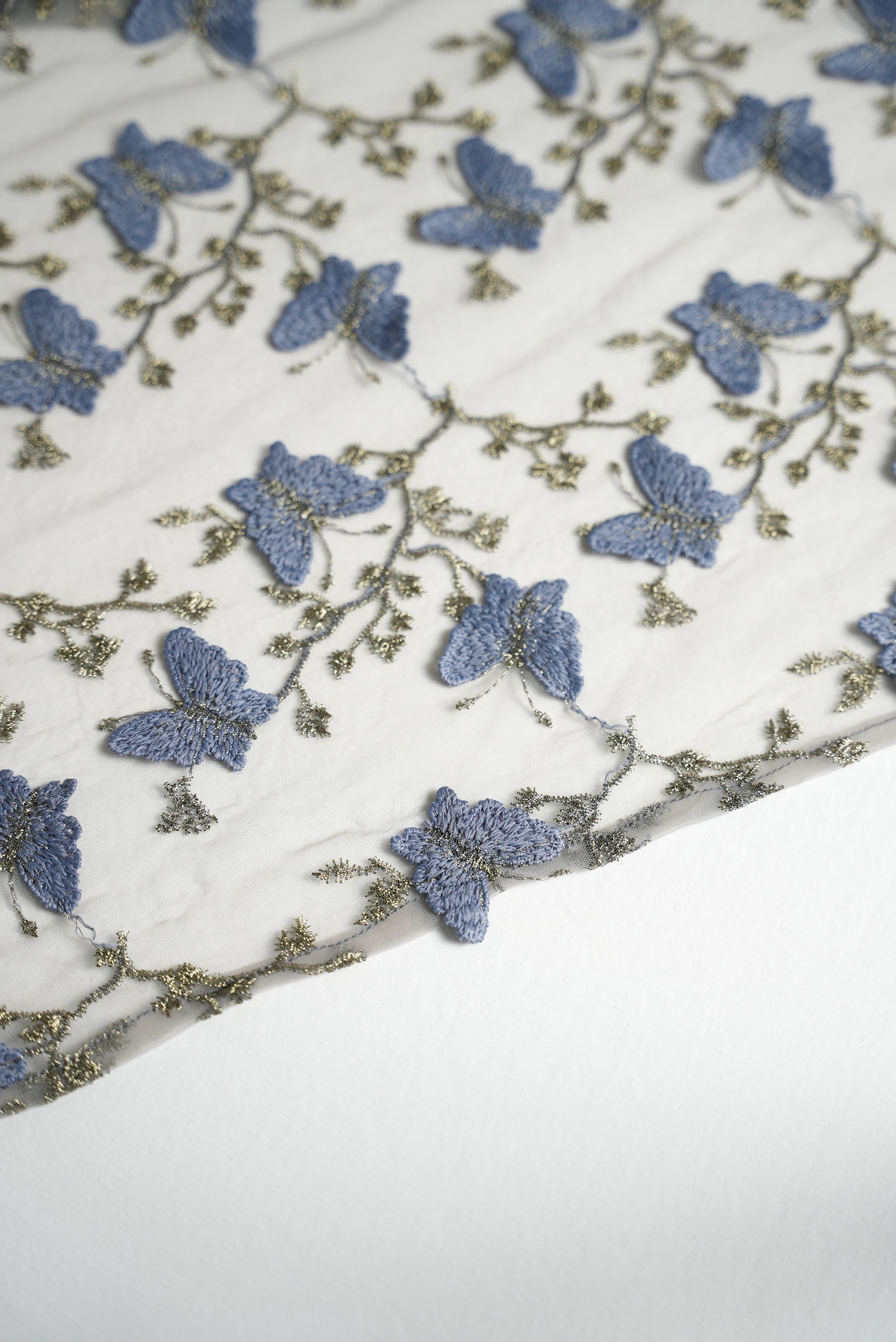 Close up shot of a saree edge with blue butterfly appliques and gold vine embroidery throughout.