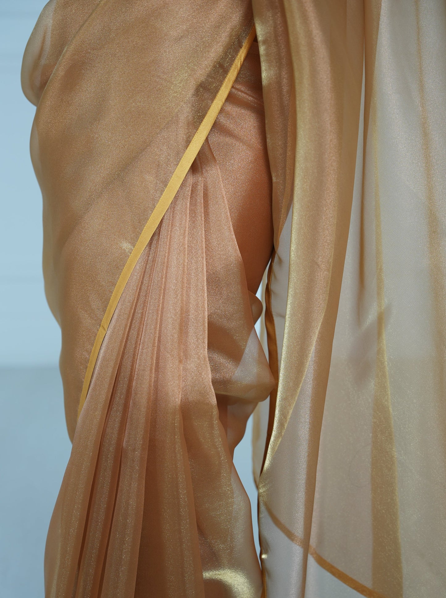 Close up of front pleats on a copper organza saree with copper satin border.