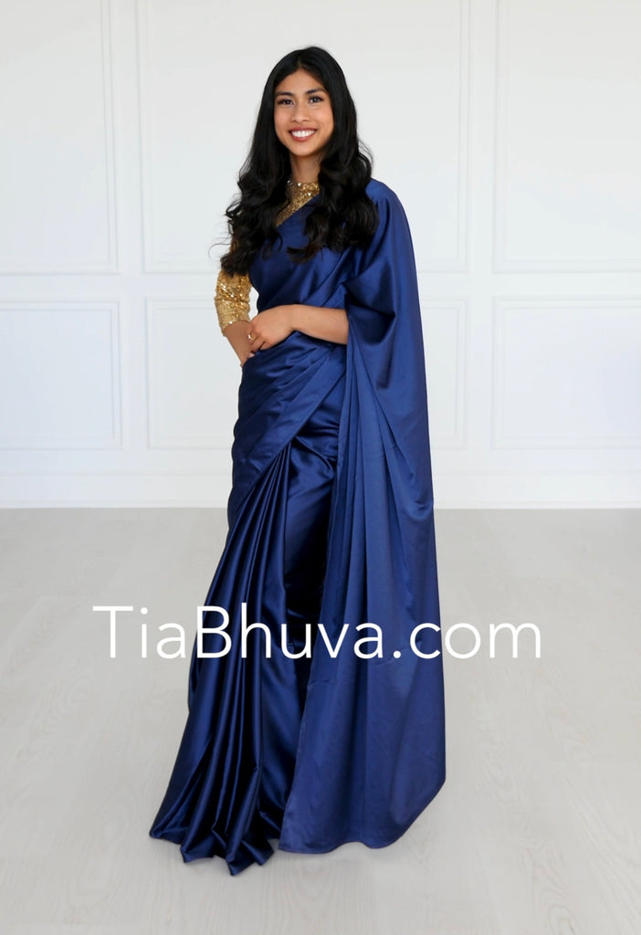 Model wearing a 3/4 sleeve light gold sequin crop top and draped in a sapphire blue satin silk saree.